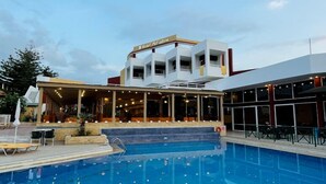 Un hotel con piscina, mobiliario exterior y una zona cubierta con un cartel que dice "Hotel Palladium".