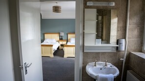 A hotel room with a bed, bedside tables, a mirror, a sink, and a towel.