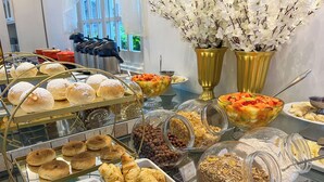 Monipuolinen buffet, jossa on tarjolla erilaisia ruokia, kuten leivonnaisia, hedelmiä ja mysliä.