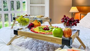 A bed with a breakfast tray containing fruits and bread, a bedside lamp, and a view of greenery through a window. - Pousada Nacional Inn Campos do Jordão (Campos do Jordão)