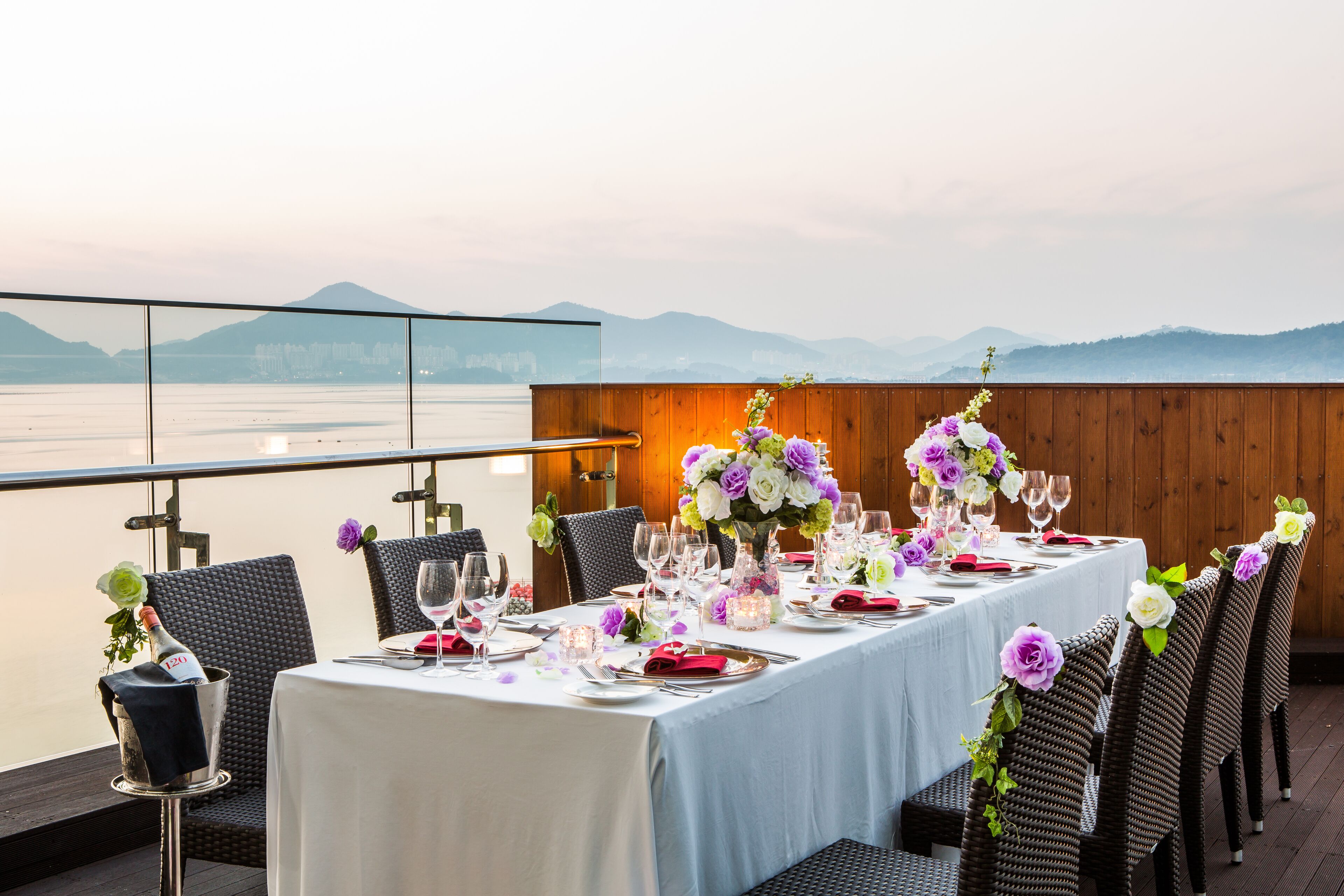 A table set for a meal with a view of the sea and mountains.