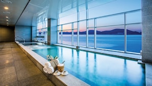 Ein modernes Hallenbad mit großem Fenster mit Blick auf ein Gewässer und ferne Berge.