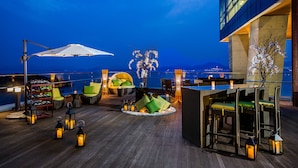 Eine Dachterrasse mit Außenbereich, einschließlich Stühle und Tische, sowie einem großen Sonnenschirm.