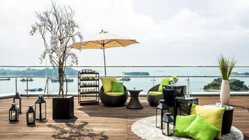 A deck with outdoor furniture, a potted tree, and a view of the water.