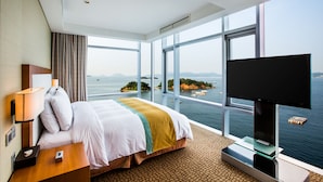 Ein Hotelzimmer mit einem großen Bett, einem Fernseher und Meerblick.
