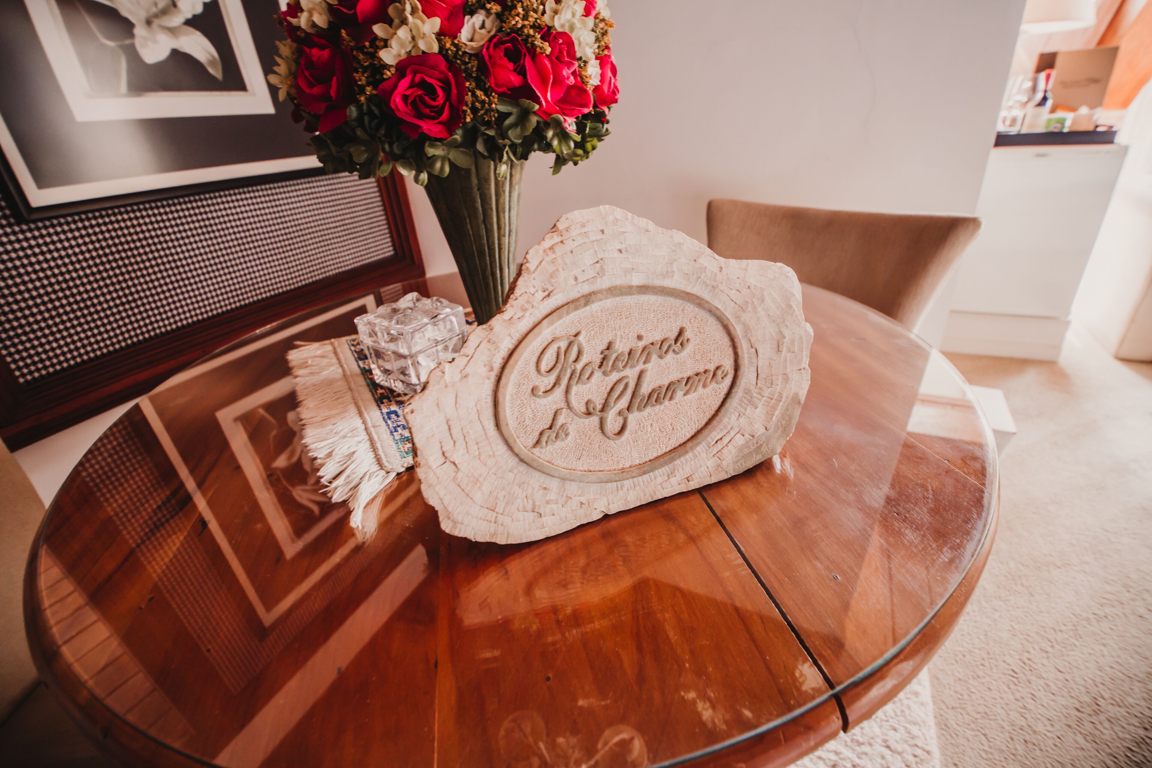 Une table ronde en verre, sur laquelle repose un sous-verre en bois portant l’inscription « Ristorante del Lago », et un vase avec des fleurs rouges et blanches.