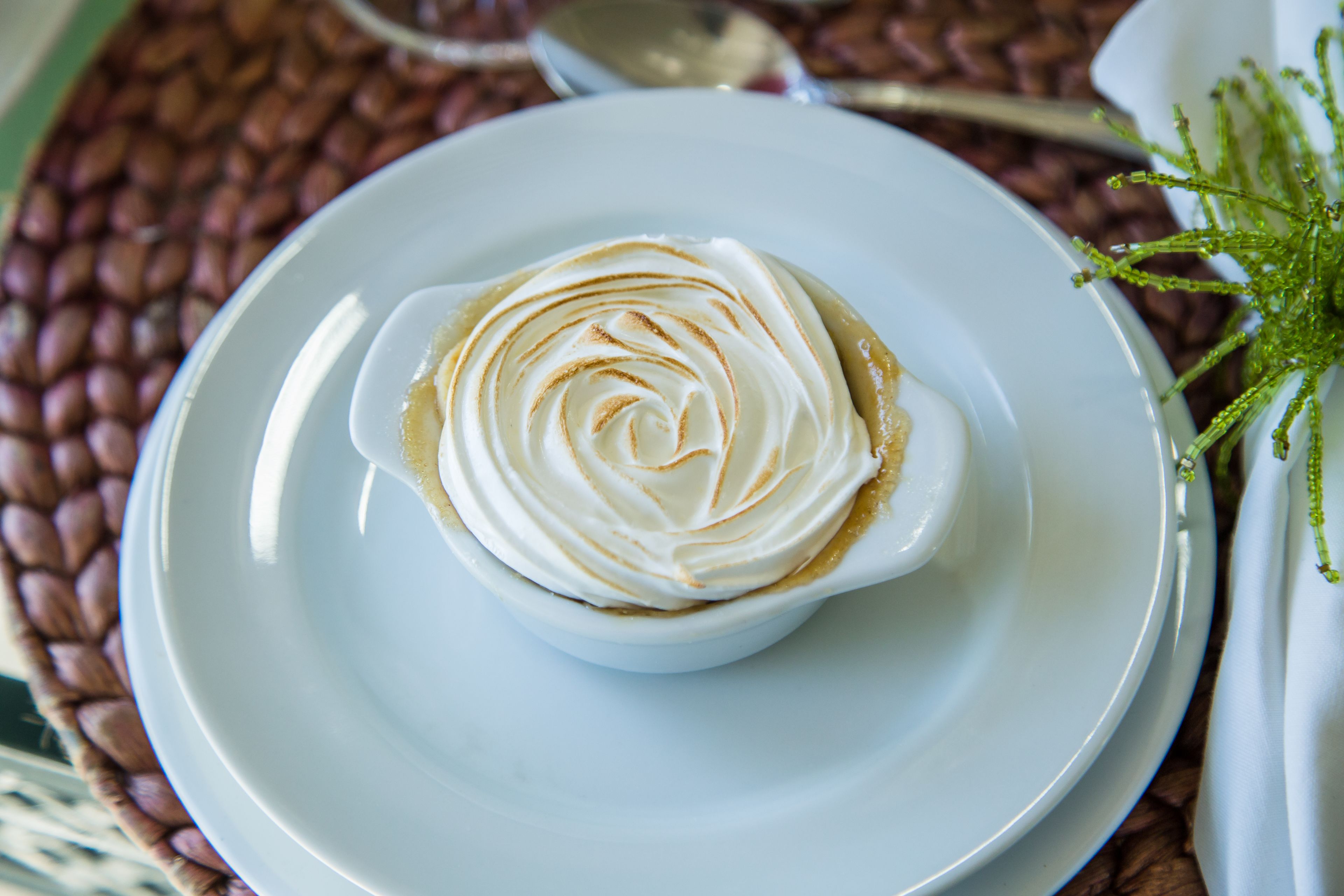 Une assiette blanche sur laquelle est servi un dessert garni de crème fouettée et décoré d’un motif ornemental.