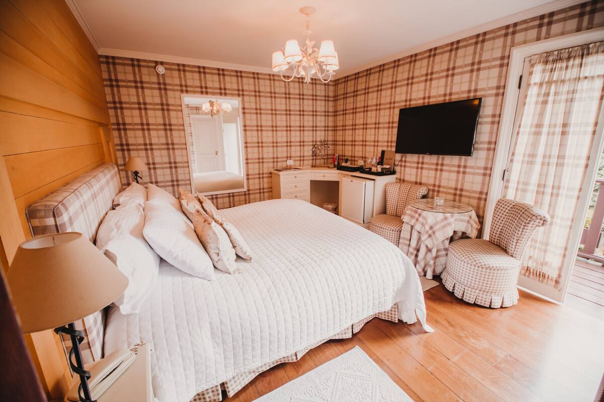 Une chambre à coucher comprenant un lit, une table de chevet, une lampe, une commode et un téléviseur fixé au mur.
