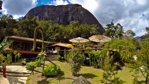 Un hotel con vistas a la montaña, mobiliario exterior y exuberante vegetación tropical.