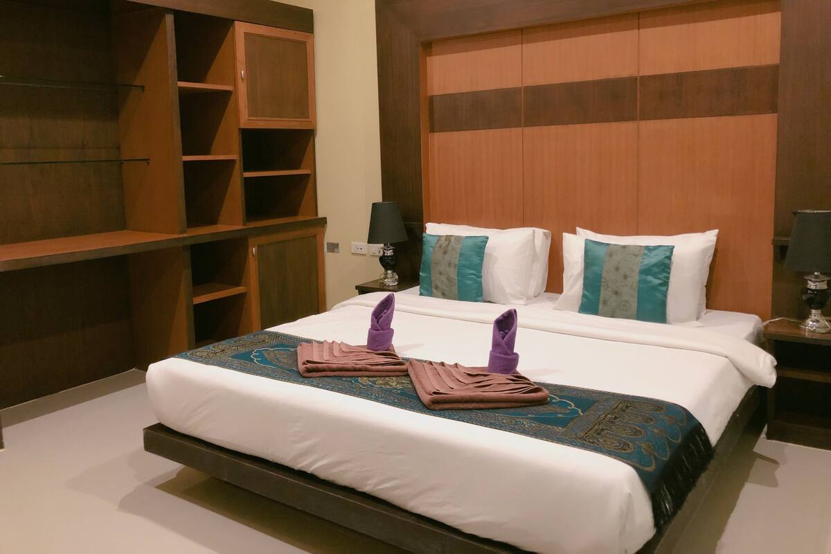A hotel room with a large bed, wooden headboard, and built-in shelving.