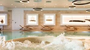 Un área de spa con una bañera de hidromasaje, sillas de mecedora de madera y obras de arte enmarcadas en las paredes.