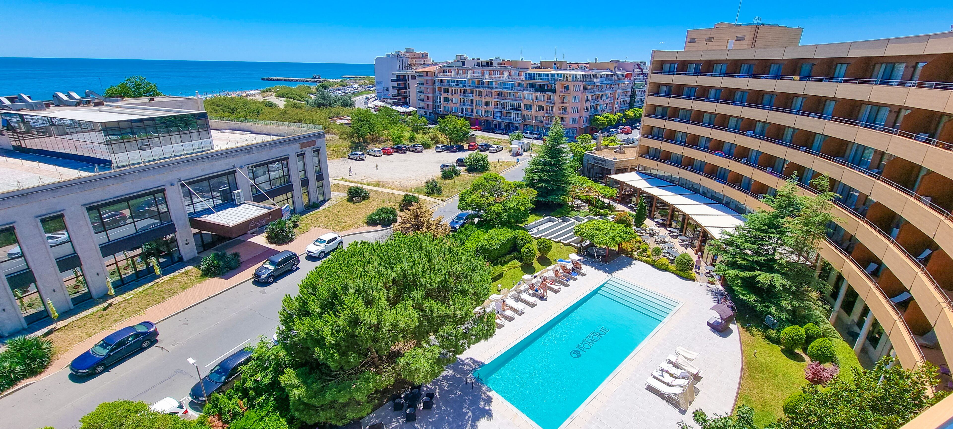 Un hotel con piscina, varias edificaciones y vista al mar.