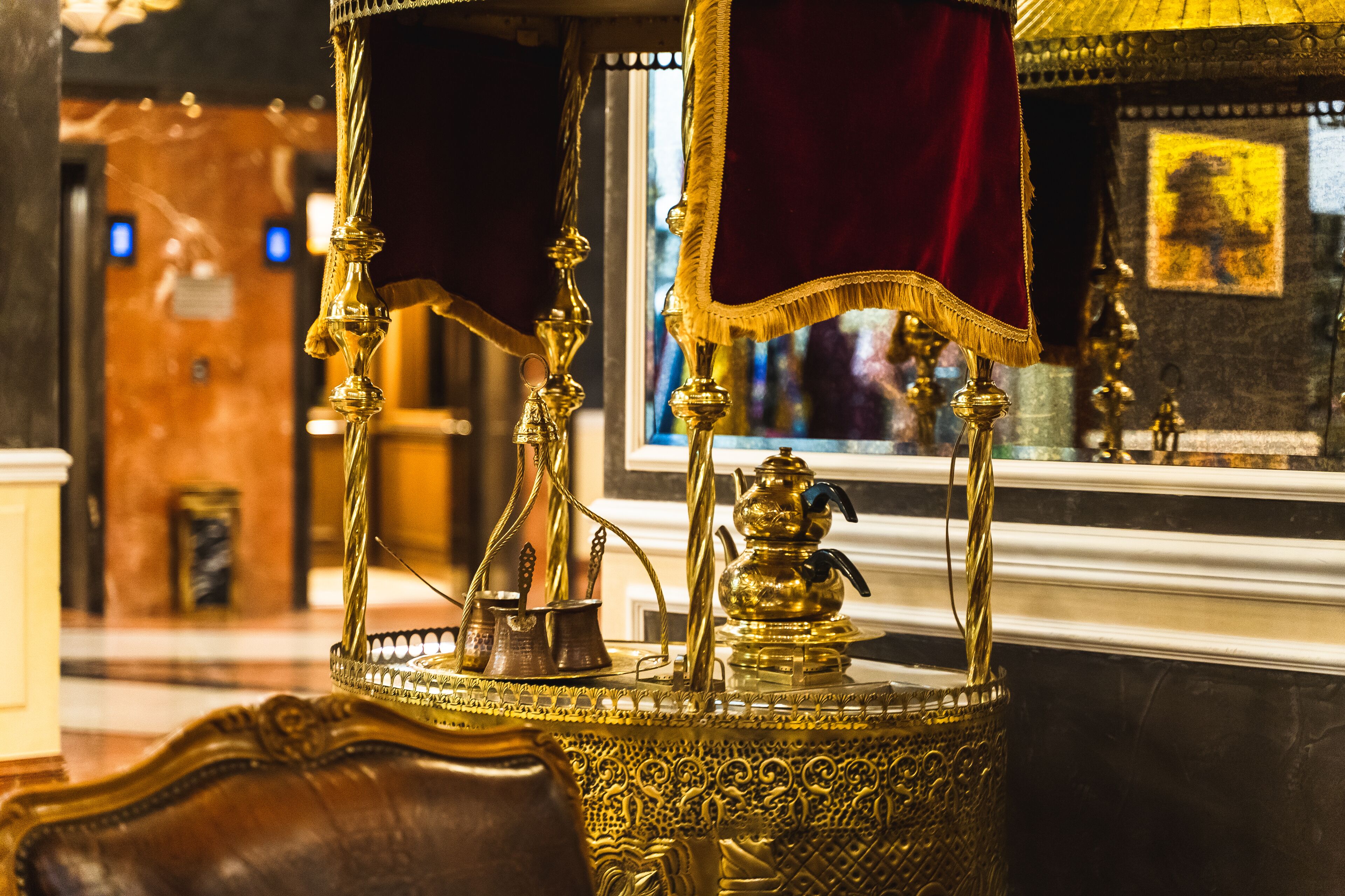 Una habitación ricamente decorada con muebles ornamentales, un espejo grande y un paño rojo.