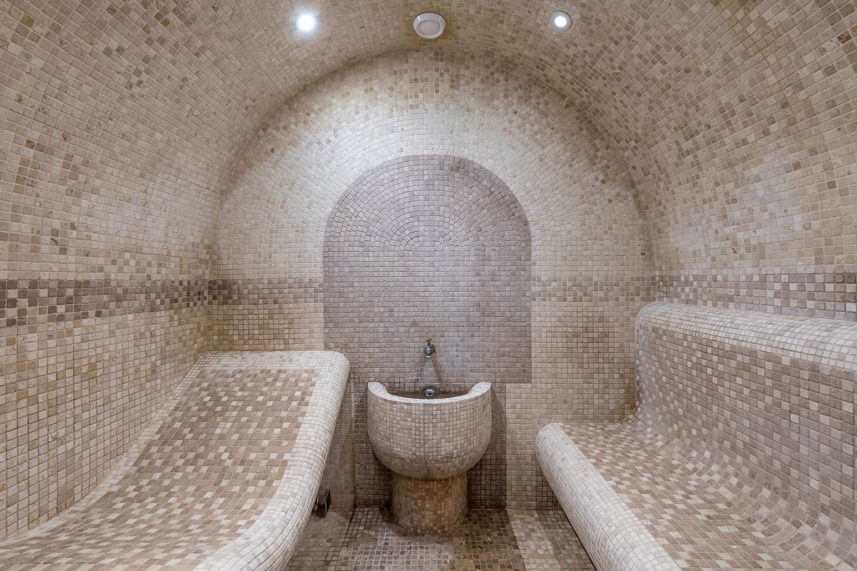 A tiled bathroom with two sinks and a central arched niche.