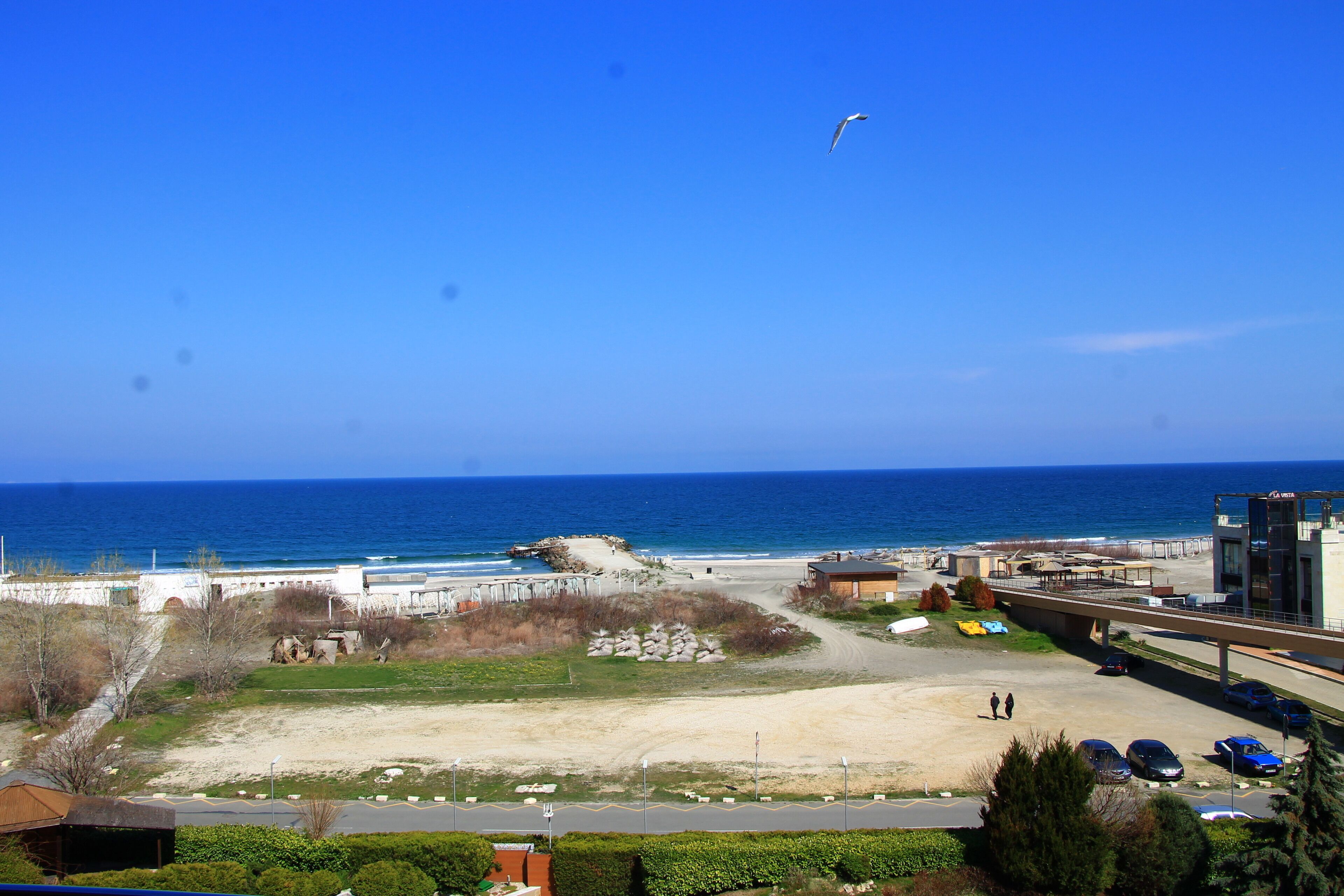 Une vue sur la côte, avec une plage, un parking et un bâtiment sur lequel on peut lire l’inscription « LA VISTA ».