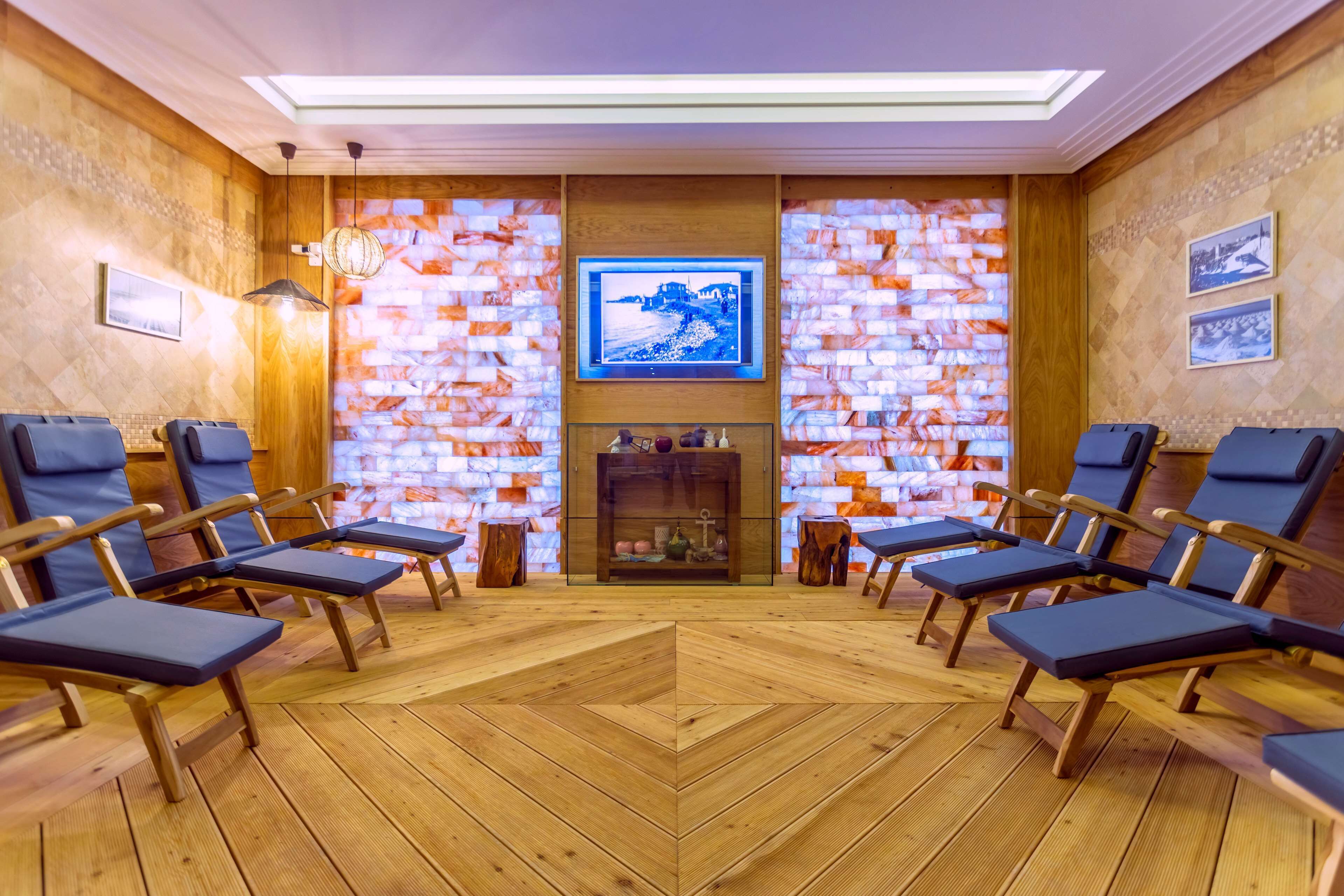 A room with wooden flooring, a fireplace, and a television mounted on the wall.