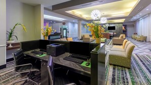 A modern hotel lobby with a reception desk, seating area, and a large chandelier.