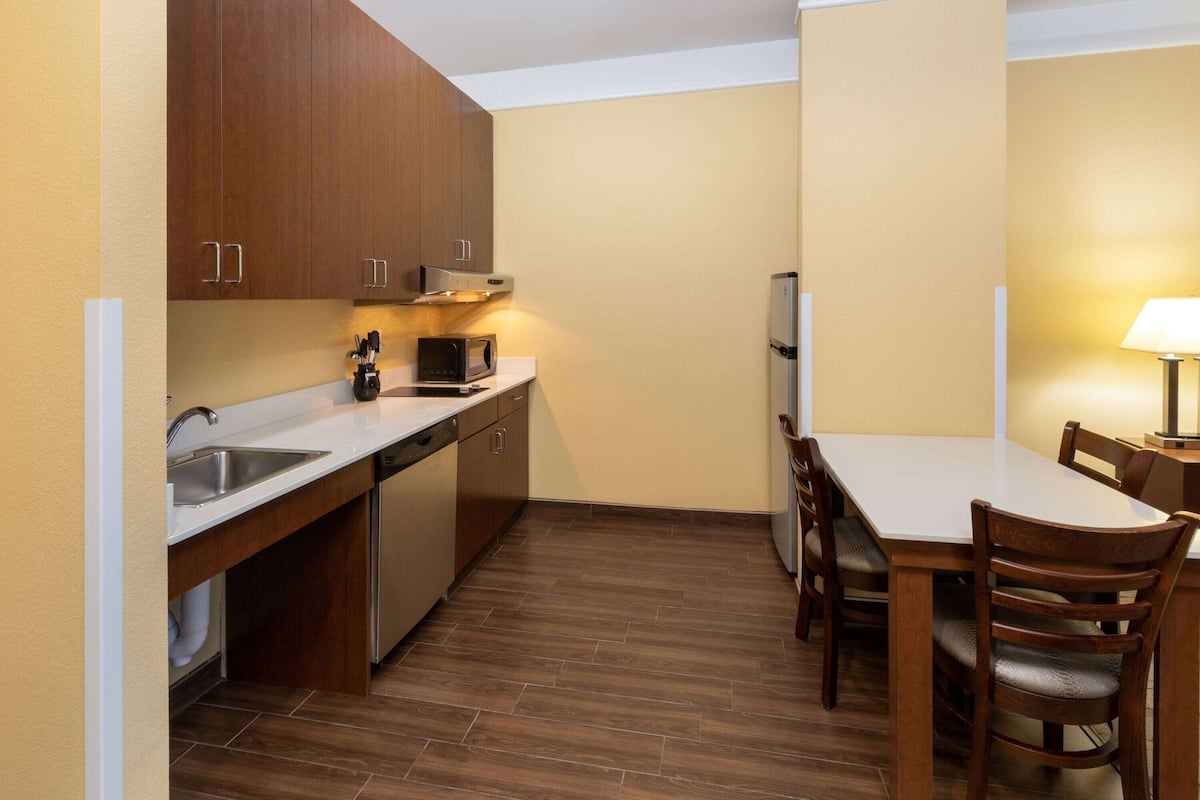 A compact kitchen with wooden cabinets, a microwave, and a refrigerator.
