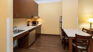 Una cocina compacta con armarios de madera, un microondas y un refrigerador.