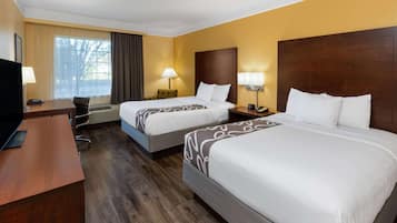 Habitación de hotel con dos camas, un escritorio y un televisor.