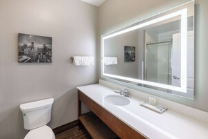 A modern bathroom with a white sink, large mirror, and two black-and-white cityscape pictures on the wall.
