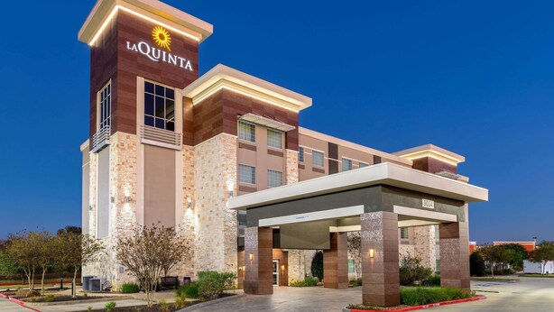 A La Quinta hotel with a modern design, featuring a prominent entrance and a well-lit facade.