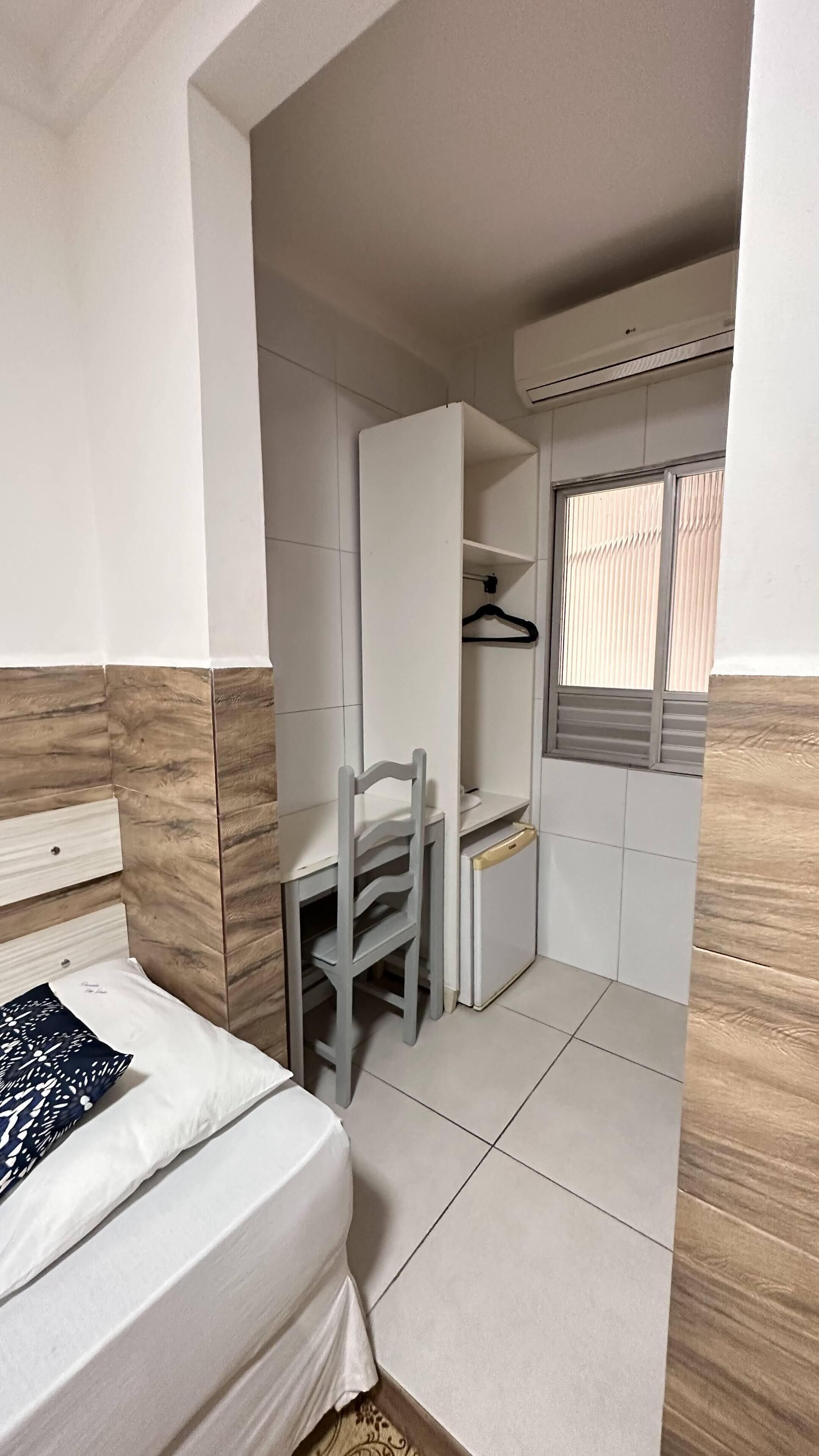Un dormitorio pequeño con cama, escritorio, silla y armario.