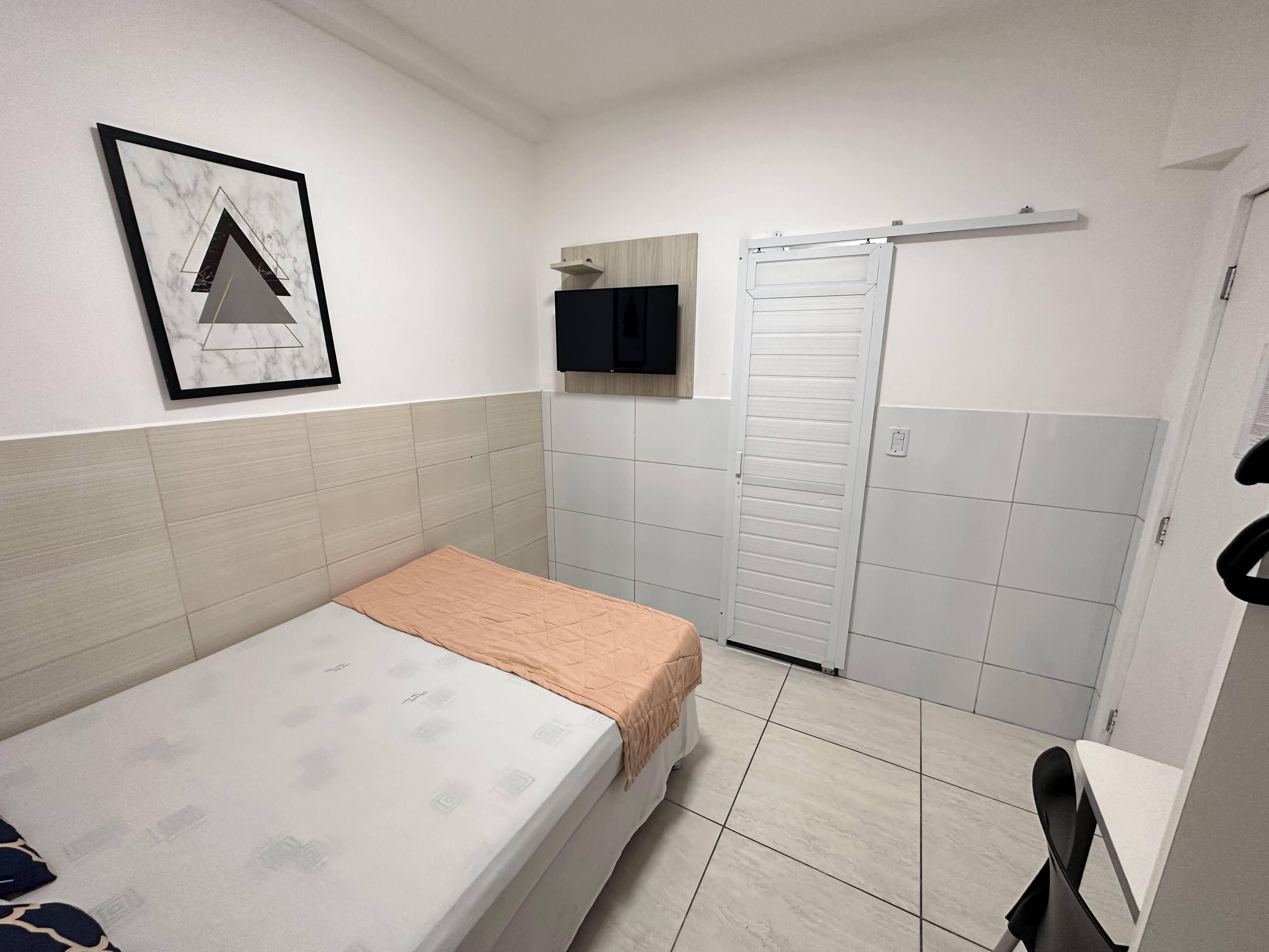 A small, clean room with a bed, a TV, and a sliding door closet.