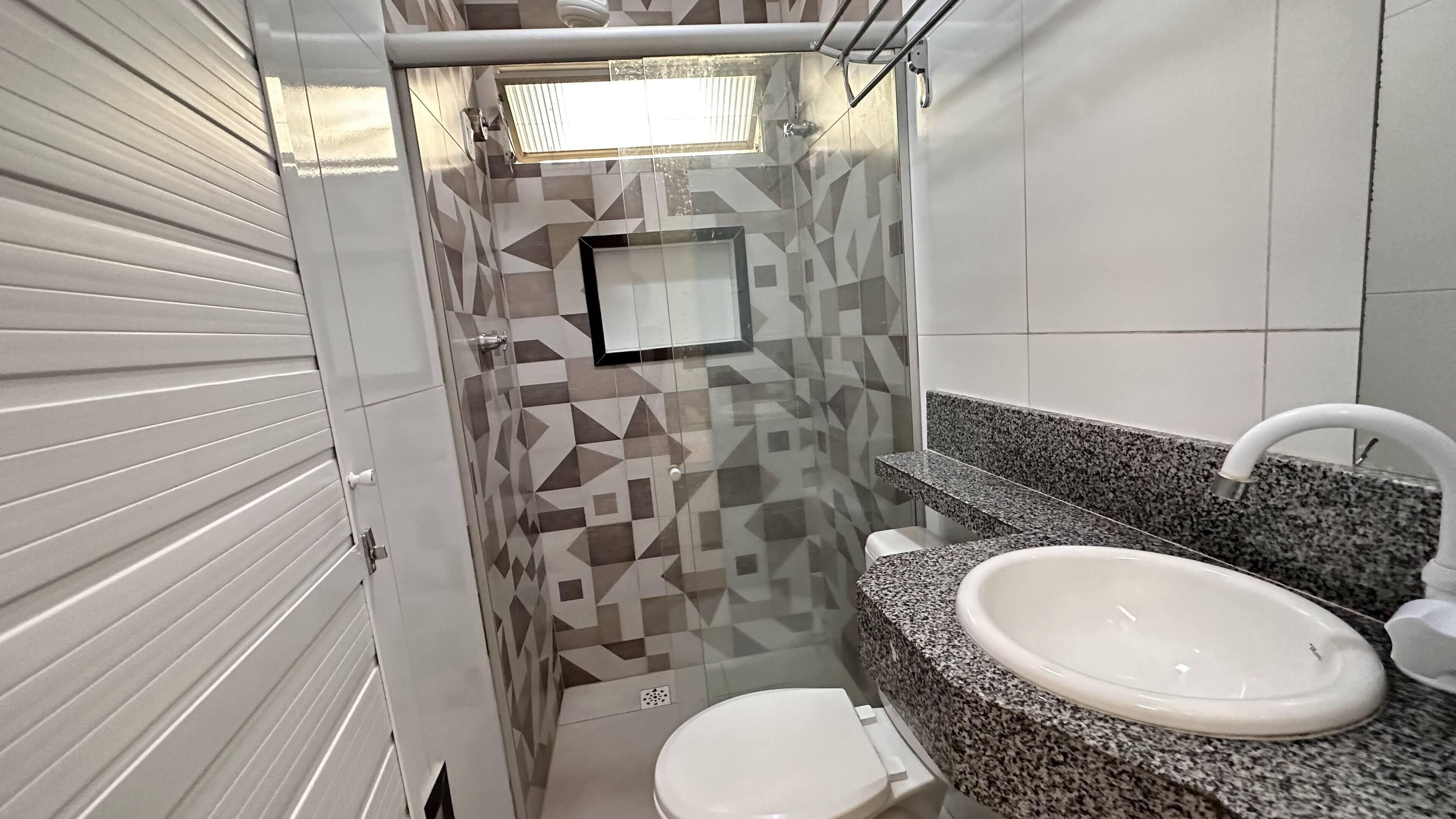 Un baño con inodoro, lavamanos y zona de ducha.