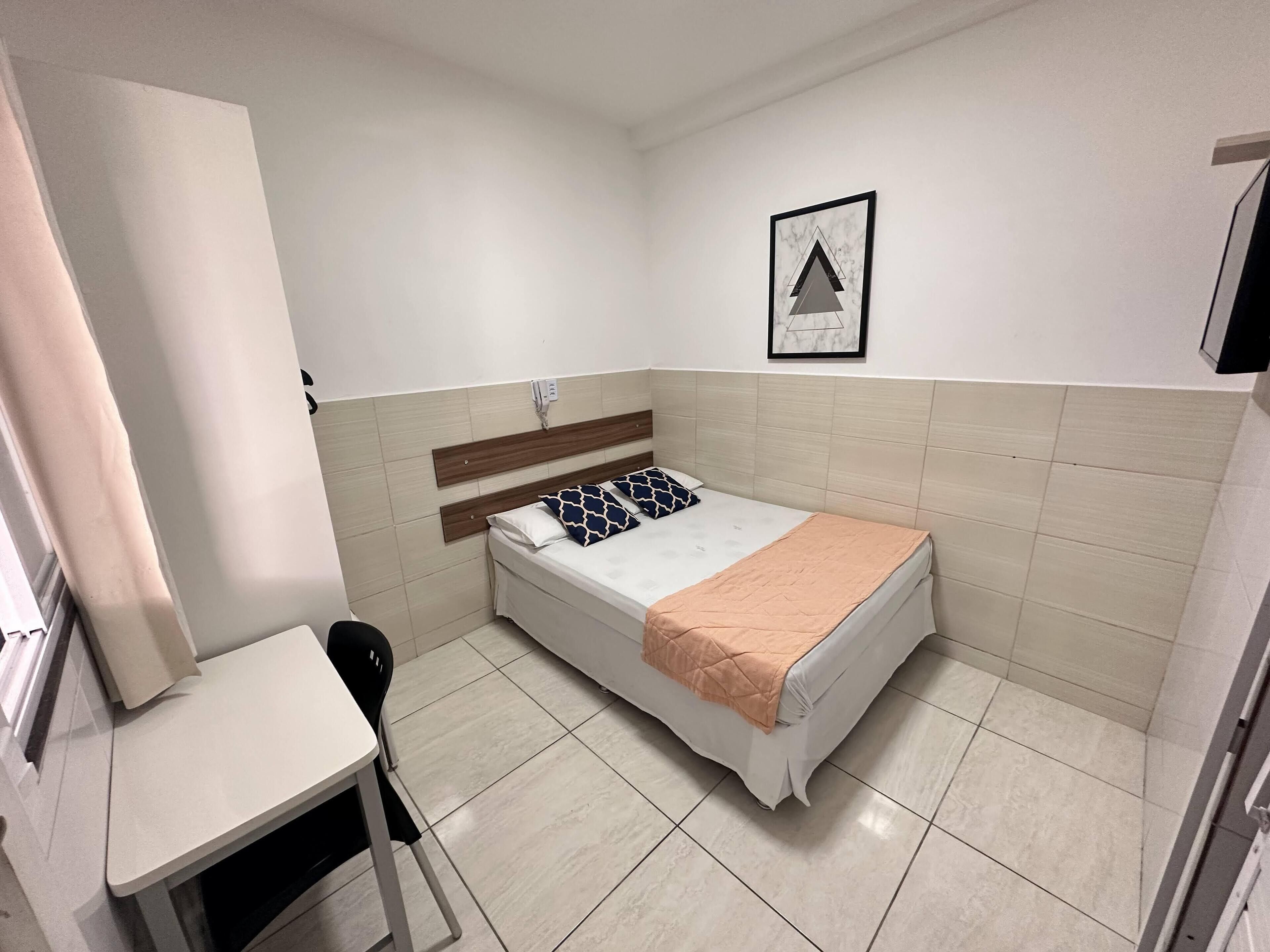 A small, clean room with a bed, a desk, and a chair.