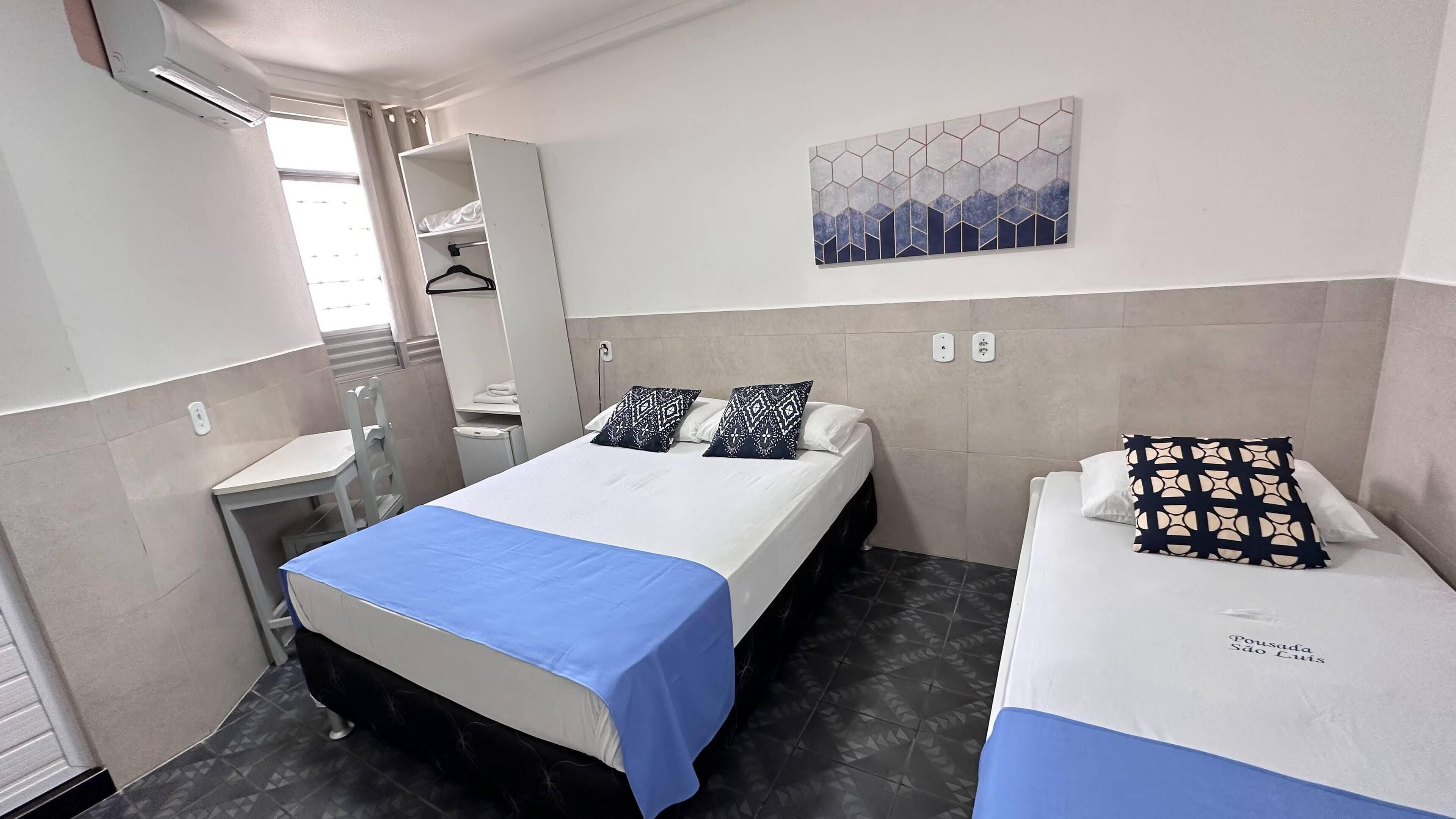 Une chambre d’hôtel comprenant un lit, un petit lit, un bureau, une chaise, une armoire et une salle de bain.