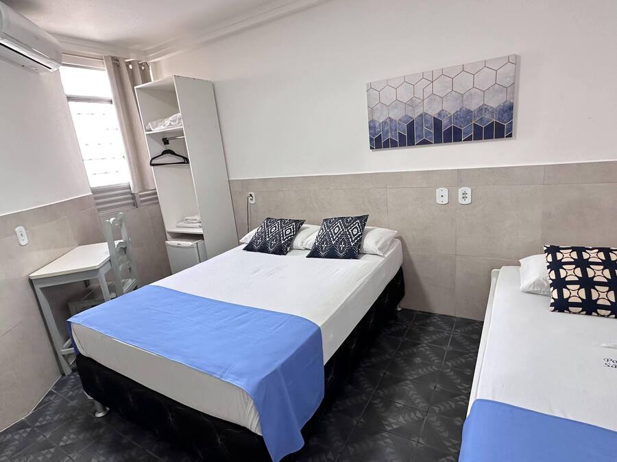 Une chambre d’hôtel comprenant un lit, un petit lit, un bureau, une chaise, une armoire et une salle de bain.