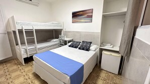 A dormitory room with bunk beds, a desk, a chair, a small refrigerator, and a painting on the wall. - Pousada São Luis (Aracaju)