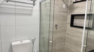 A modern bathroom with a glass-enclosed shower, a toilet, and a sink.