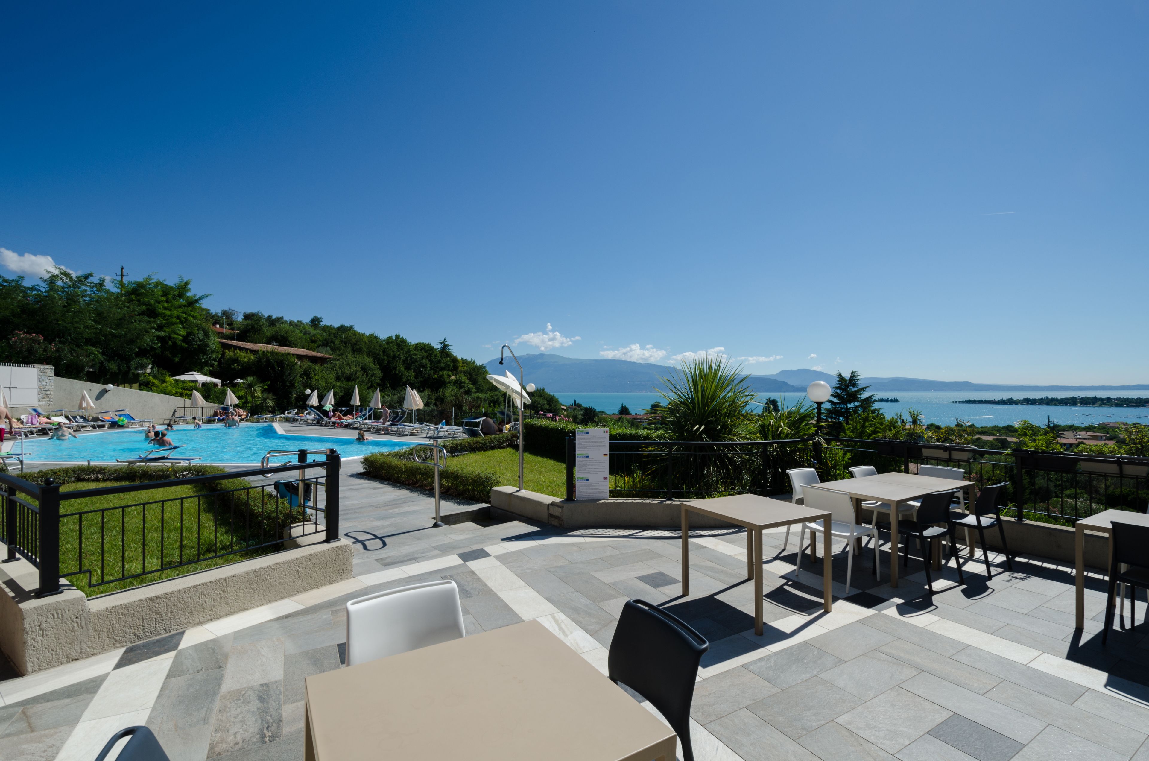 Una terraza con mobiliario exterior, una piscina y vistas al mar y las montañas.