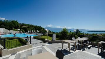 Una terraza con mobiliario exterior, una piscina y vistas al mar y las montañas.
