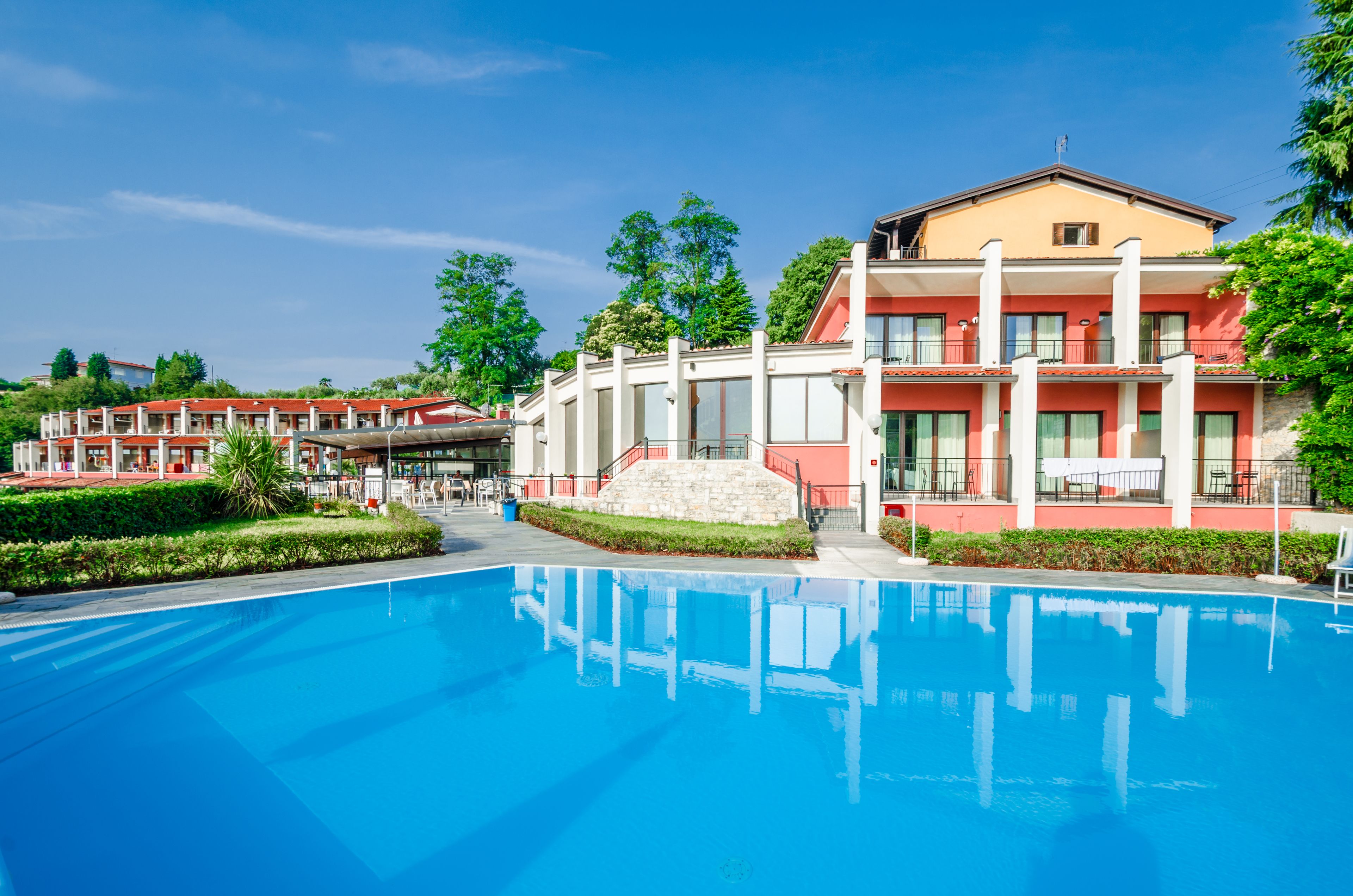 Un hotel amb piscina, diversos edificis i un jardí paisatjistic.
