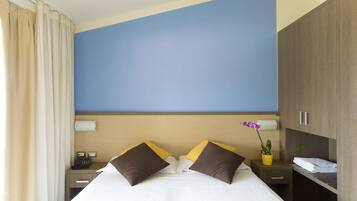 Una habitación de hotel con cama, mesitas de noche, escritorio y armario.