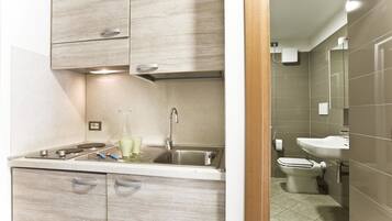 A modern kitchen with a stainless steel sink and a toilet visible in the adjacent bathroom.
