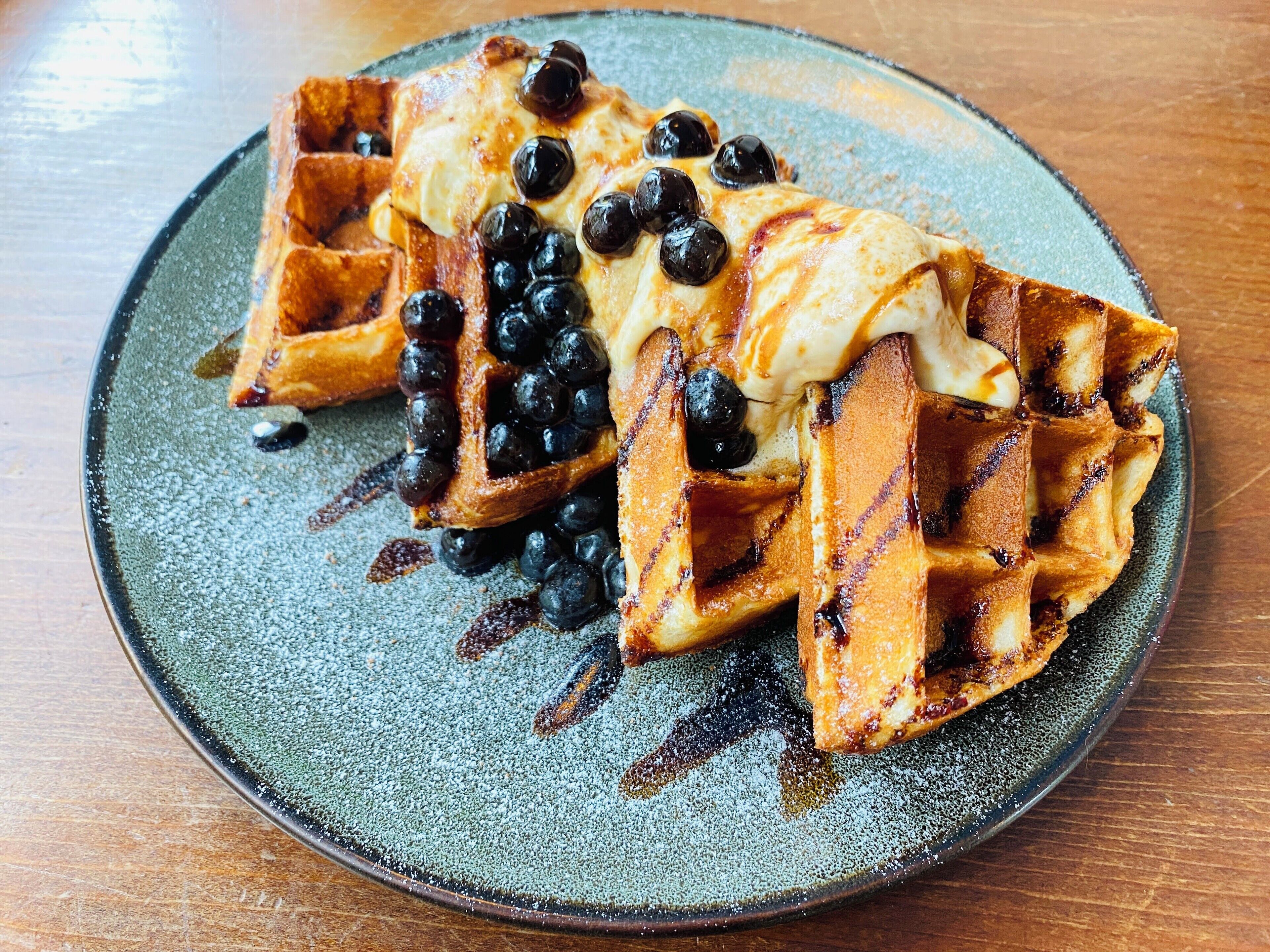 A plate with waffles and blueberries.