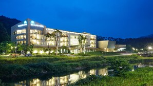 A modern hotel with multiple floors, large windows, and a well-lit entrance. - The Suites Hotel Namwon (Namwon)