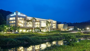 Un hotel moderno con varios pisos, amplias ventanas y una entrada bien iluminada.