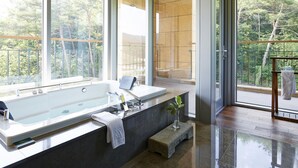 A modern bathroom with a large bathtub, a bench, and a small plant. - The Suites Hotel Namwon (Namwon)