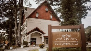 A hotel sign for Colina Premium São Francisco with a classic architectural style, a large entrance, and a well-maintained garden. - Hotel Colina São Francisco (Gramado)