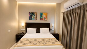 A hotel room with a large bed, two nightstands, an air conditioning unit, and two pieces of wall art. - The Orion Express (Jaipur)