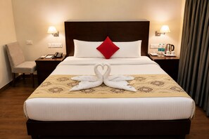 A hotel room with a bed, a chair, a nightstand, a lamp, and a curtain. - The Orion Express (Jaipur)