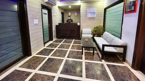 A hotel reception area with a reception desk, seating, and a tiled floor. - The Orion Express (Jaipur)