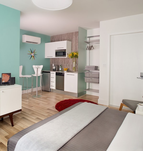 Un dormitorio moderno con cama, escritorio y kitchenette.