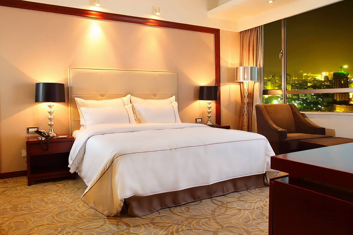 A hotel room with a large bed, two bedside tables, a desk, and a chair.