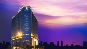 Ein hoch aufragendes Hotel mit einem gut sichtbaren Schriftzug "Grand Hotel", mehreren Etagen und einer modernen Glasfassade.